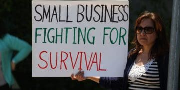 A small business owner with a sign explaining her troubles during the Covid-19 pandemic. Photo by Gene Gallin/Unsplash