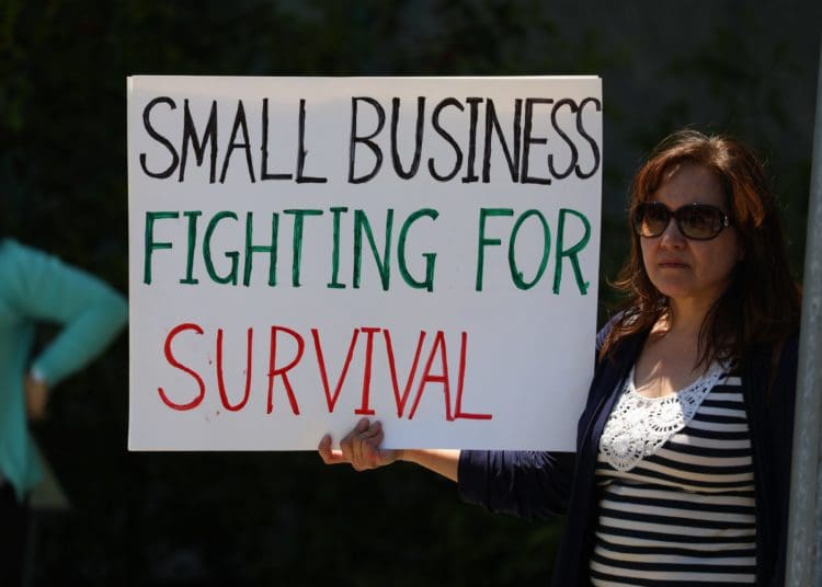 A small business owner with a sign explaining her troubles during the Covid-19 pandemic. Photo by Gene Gallin/Unsplash