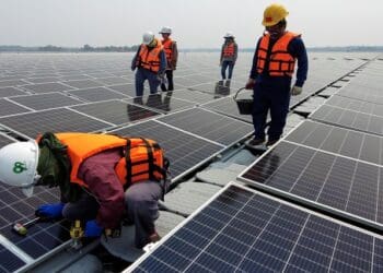 A worker kneels by one of the solar cell panels over the water surface of Sirindhorn Dam in Ubon Ratchathani, Thailand April 8, 2021. Picture taken April 8, 2021 with a drone. REUTERS/Prapan Chankaew